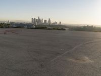 the person riding his bike through the parking lot near a city skyline as he goes off into the distance