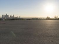 the person riding his bike through the parking lot near a city skyline as he goes off into the distance