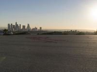 the person riding his bike through the parking lot near a city skyline as he goes off into the distance