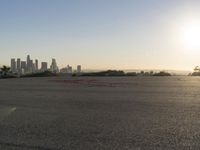 the person riding his bike through the parking lot near a city skyline as he goes off into the distance