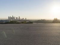 the person riding his bike through the parking lot near a city skyline as he goes off into the distance