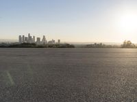 the person riding his bike through the parking lot near a city skyline as he goes off into the distance