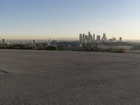 the person riding his bike through the parking lot near a city skyline as he goes off into the distance