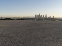 the person riding his bike through the parking lot near a city skyline as he goes off into the distance