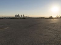 the person riding his bike through the parking lot near a city skyline as he goes off into the distance