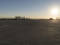 the person riding his bike through the parking lot near a city skyline as he goes off into the distance