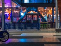 the entrance to the building with many lights lit up and a bicycle parked outside and behind the building