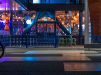 the entrance to the building with many lights lit up and a bicycle parked outside and behind the building