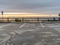 an empty parking lot at dusk in a large city with skyscrapers in the distance