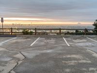 an empty parking lot at dusk in a large city with skyscrapers in the distance