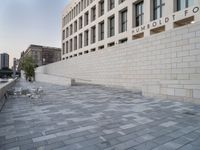 there is a brick walkway in front of a building with a white brick wall on the side