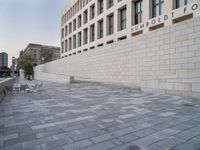 there is a brick walkway in front of a building with a white brick wall on the side