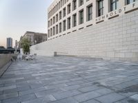 there is a brick walkway in front of a building with a white brick wall on the side