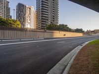 the empty road is seen between the tall buildings on either side of the freeway side