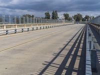 a train crossing a long bridge near an airport with a ramp and a person on a cell phone waiting