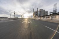 the sun is setting on the road in the city with buildings and street signs in the foreground