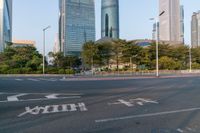 an intersection with the road empty and two way signs painted on it and some buildings in the background