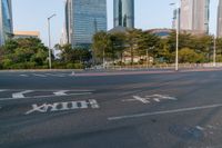 an intersection with the road empty and two way signs painted on it and some buildings in the background