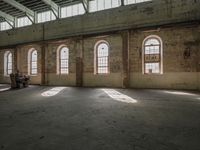 an empty warehouse with lots of windows in it's space, and a wooden bench below