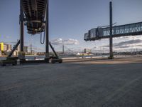 an air port filled with lots of trucks under a sky overpass, and clouds over it