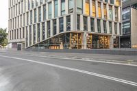 a very long and empty road in a city area with a tall building on the side