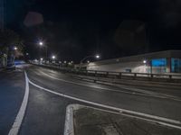 a quiet highway at night, with a building in the distance, in front of trees