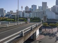 a highway going over an intersection in front of tall buildings on a clear day in the city