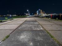 the bench is on a city sidewalk by the water in the night time, the view is incredible