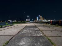 the bench is on a city sidewalk by the water in the night time, the view is incredible