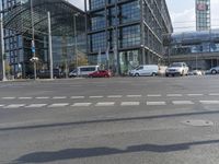 people are walking in a city intersection with a blue car driving past them on the road