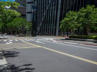 a city intersection with many buildings and trees on both sides of the road and on the sidewalk