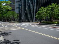 a city intersection with many buildings and trees on both sides of the road and on the sidewalk