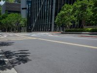 a city intersection with many buildings and trees on both sides of the road and on the sidewalk