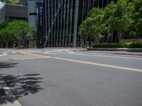 a city intersection with many buildings and trees on both sides of the road and on the sidewalk