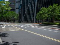 a city intersection with many buildings and trees on both sides of the road and on the sidewalk