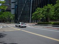 a city intersection with many buildings and trees on both sides of the road and on the sidewalk