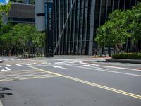 a city intersection with many buildings and trees on both sides of the road and on the sidewalk