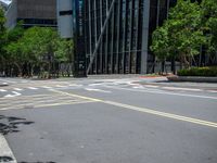 a city intersection with many buildings and trees on both sides of the road and on the sidewalk