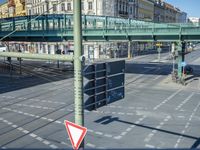 the cars on the street are stopped at the intersection with a pedestrian and a sign