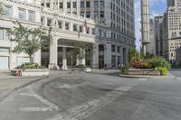 a city intersection with many tall buildings and cars in front of it and people riding around
