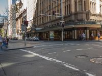 an intersection with some people walking on it and a building and traffic light in the background