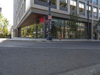 an intersection on a street corner and an office building in the background, with a pedestrian crossing sign and building on either side