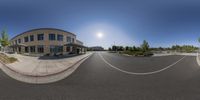 a fish eye lens lens shot a building in a parking lot, and an intersection with parked cars