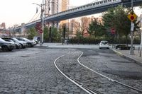 an intersection in a city, with a train tracks running between the two roads and a building