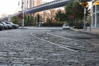 an intersection in a city, with a train tracks running between the two roads and a building