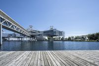 a boat dock next to a bridge over water in front of a building with a big glass windows