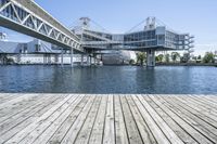 a boat dock next to a bridge over water in front of a building with a big glass windows