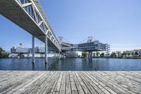 a boat dock next to a bridge over water in front of a building with a big glass windows