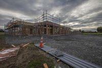 a house being built with scaffolding in the background of a cloudy sky and some grass