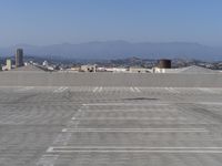 a parking lot with mountains in the background and blue sky overhead, viewed from above